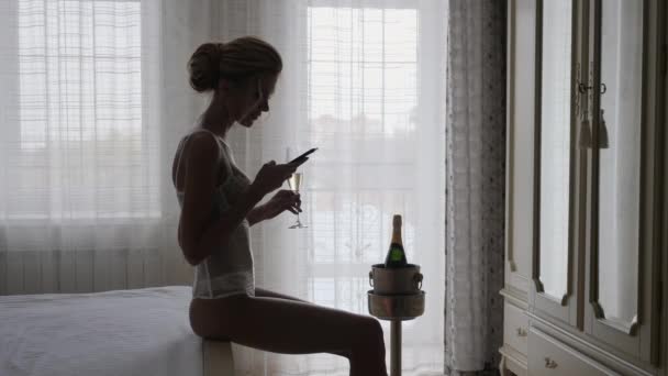 Silhueta de uma menina bonita com um telefone contra a janela
 - Filmagem, Vídeo