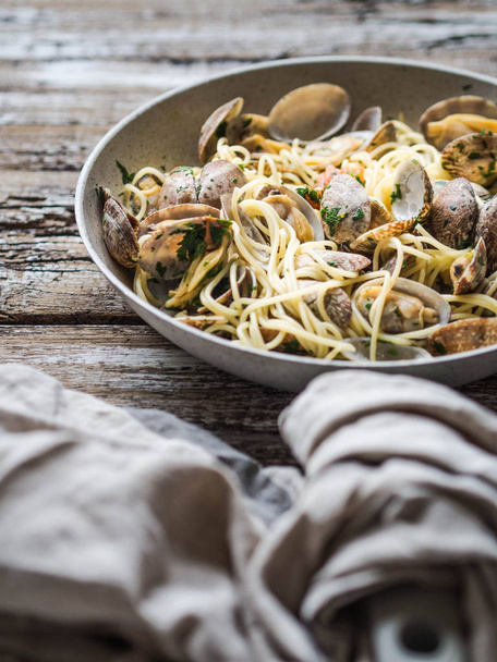 Spaghetti with clams, tomatoes, garlic and parsley in a pan - Φωτογραφία, εικόνα