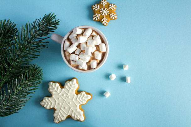 Hot chocolate with marshmallows in the white cup and Christmas composition on the blue  background.Copy space.Top view. - Foto, imagen
