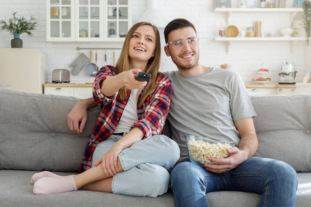 Young happy family watching tv, sitting on sofa at kitchen - Foto, Imagen