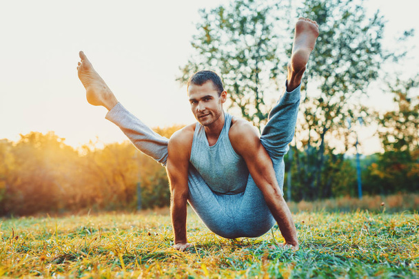 Hombre yogui entrenando en el parque de la ciudad. Luz cálida del atardecer
. - Foto, imagen