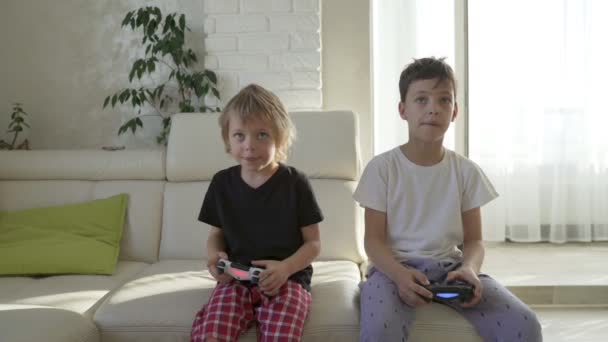 Two kids emotionally playing videogames at home at sunny morning - 映像、動画
