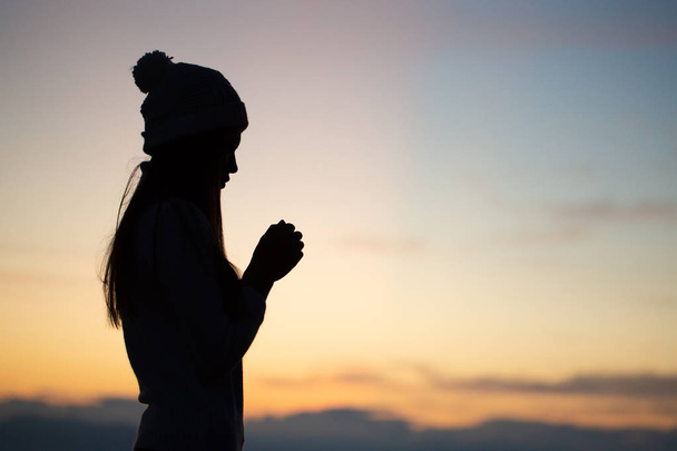 Silhouette einer Frau, die über dem schönen Sonnenaufgang betet. - Foto, Bild