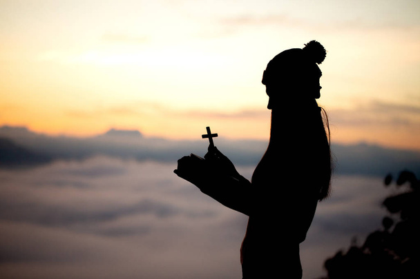 祈っている女性のシルエット美しい空を背景にクロス - 写真・画像