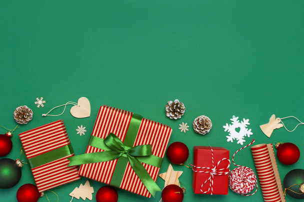 Подарочные коробки, рождественские шары, игрушки, еловые шишки, лента на зеленом фоне. Праздник, поздравления, новогодние подарки Рождественские открытки 2019 года. Плоский вид сверху, копировальное пространство
. - Фото, изображение