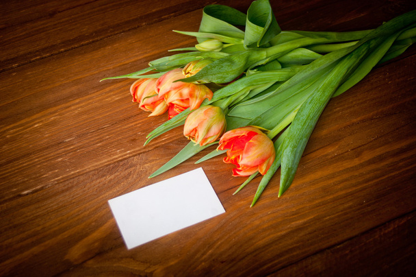 Tulipanes y tarjeta en blanco en tableros de madera viejos
 - Foto, Imagen