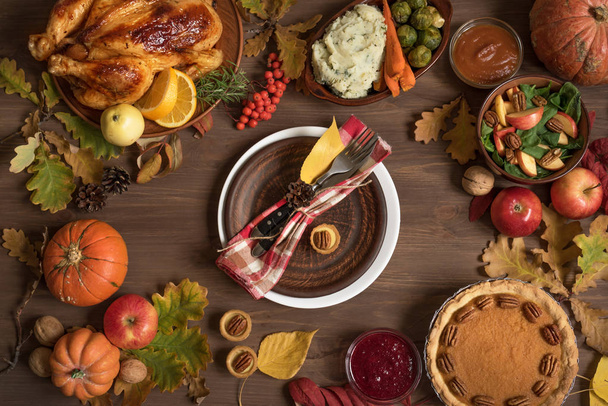 Thanksgiving dinner background with turkey and all sides dishes, pumpkin pie, fall leaves and seasonal decor around plate, top view. - Foto, Bild
