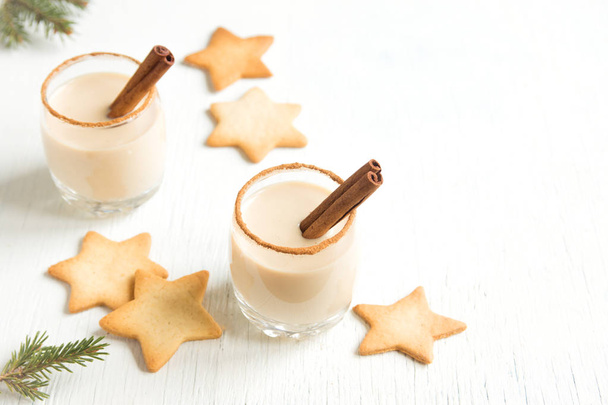 Eggnog with cinnamon and nutmeg for Christmas and winter holidays. Christmas Eggnog, gingerbread cookies isolated on white background. - Valokuva, kuva