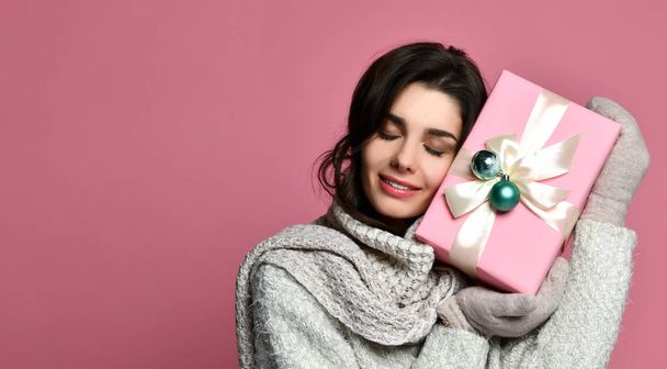 Cheerful woman in grey sweater holding gift box and having fun - Фото, зображення