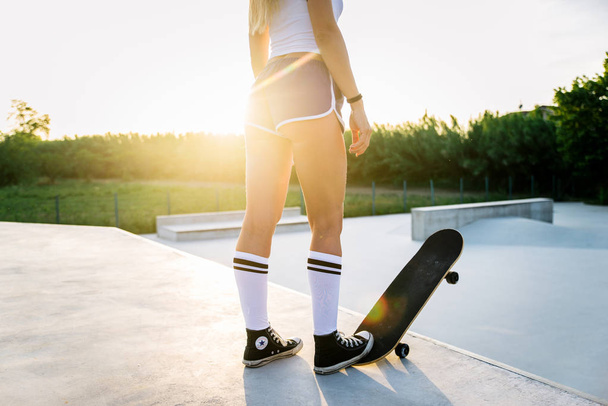 Stylish young woman skating outdoors - Pretty female skater playing with her skate - Φωτογραφία, εικόνα