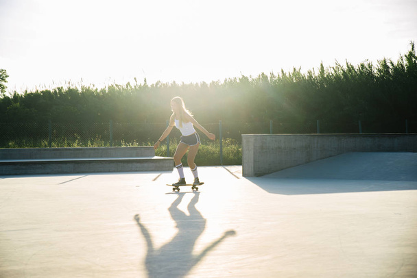 Stylish young woman skating outdoors - Pretty female skater playing with her skate - Foto, Imagem