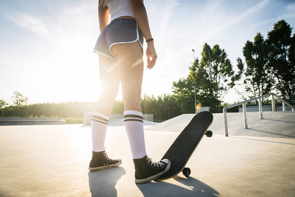 Stylish young woman skating outdoors - Pretty female skater playing with her skate - Foto, Imagen