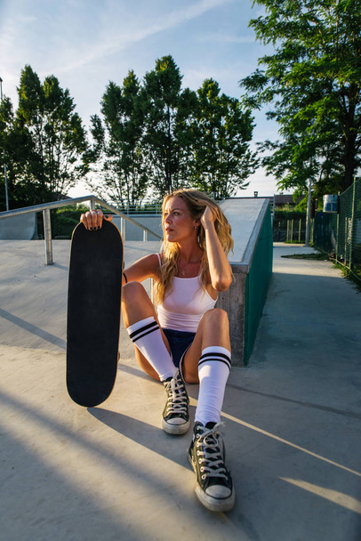 Stylish young woman skating outdoors - Pretty female skater playing with her skate - Photo, Image