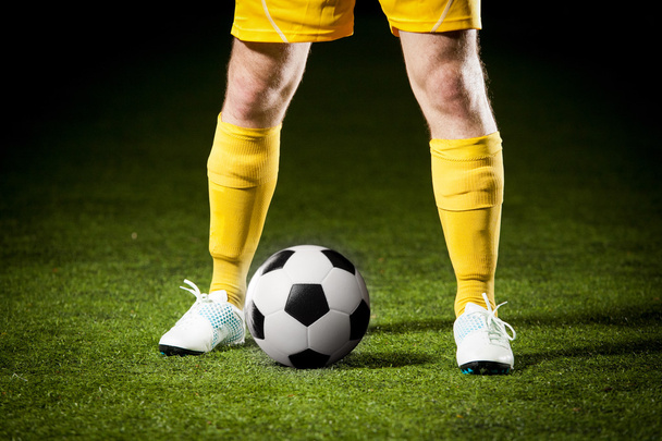 Soccer ball and a feet of a soccer player - Fotó, kép