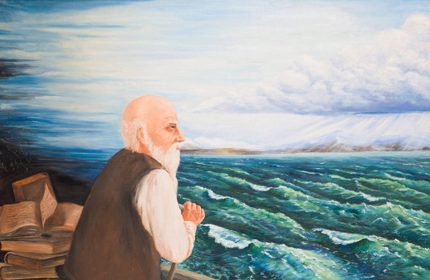 A gray-haired bearded old man stands by the lake and looks into the distance - Foto, imagen
