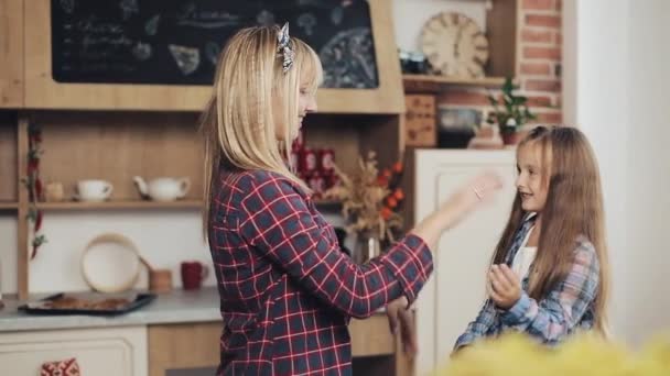 Charming mom and daughter have fun in a cosy kitchen - Materiał filmowy, wideo