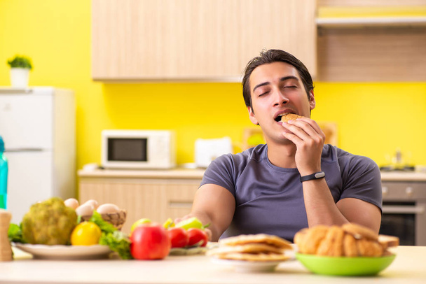Homem tendo escolha difícil entre alimentos saudáveis e não saudáveis
 - Foto, Imagem
