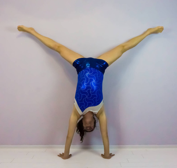 акробатическая гимнастика средняя раздробленная стойка на руках, созданная молодой трансгендерной девушкой в синем блестящем трико
 - Фото, изображение