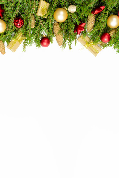 Christmas border isolated on white, composed of fresh fir branches, cones and ornaments in red and gold - Фото, зображення