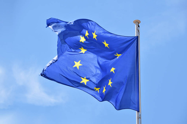 Zbliżenie flagi UE, Unia Europejska machająca i wiejąca na wietrze nad błękitnym niebem, widok z niskiego kąta - Zdjęcie, obraz