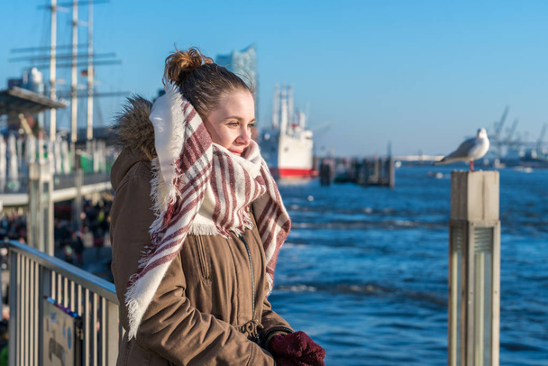 Młoda kobieta stoi na molo, patrząc na wodę w Wira Hamburg - Zdjęcie, obraz