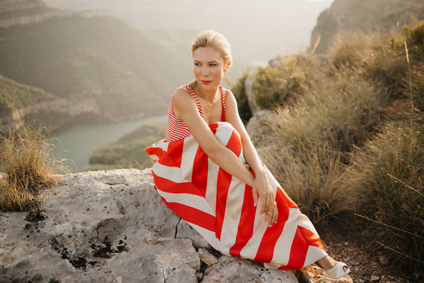 優雅なブロンド若い女性オレンジ日没で古代峡谷のポーズします。スペイン - 写真・画像