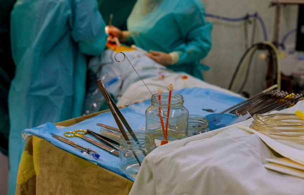 Nahaufnahme chirurgischer Instrumente auf dem Tisch für Operationen mit Kollegen, die Operationen im Operationssaal durchführen - Foto, Bild