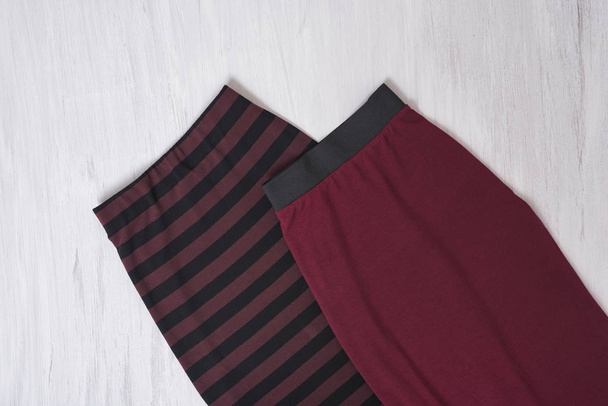 Two burgundy skirts on wooden background. Fashionable concept - Photo, Image