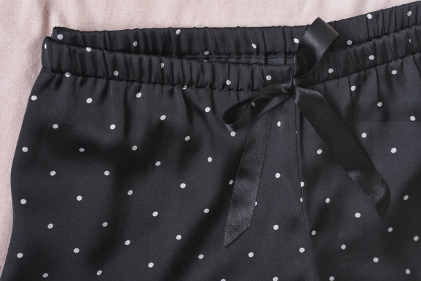 Black satin shorts. Fashion concept. Details, close up - 写真・画像