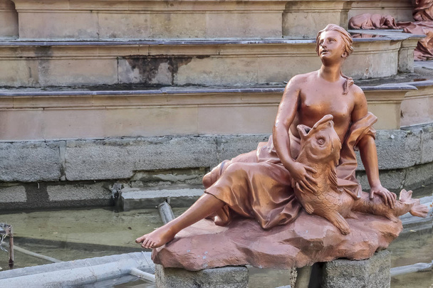 escultura pintada de plomo de una criada jugando con un tritón en la fuente los baños de diana en los jardines del palacio real de la granja de san ildefonso
 - Foto, Imagen