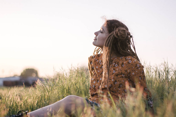 Portrait of beautiful hippie woman with dreadlocks in the woods at sunset having good time outdoors - Photo, Image