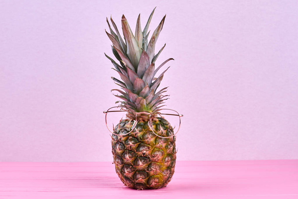 Pineapple in eyeglasses on pink background. - Фото, зображення