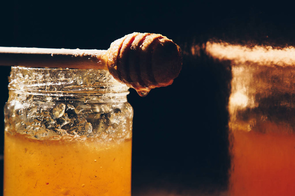 jar of honey with bagels on wooden table close up with honey dipper on black background - 写真・画像