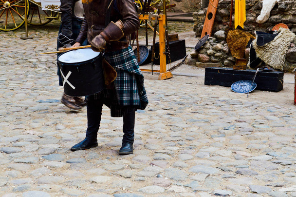 Ένα σκωτσέζικο πολεμιστής, στρατιώτης, μουσικός με παραδοσιακή φορεσιά με μια φούστα το τύμπανο χτυπά στην πλατεία του μεσαιωνικού κάστρου παλιά. - Φωτογραφία, εικόνα