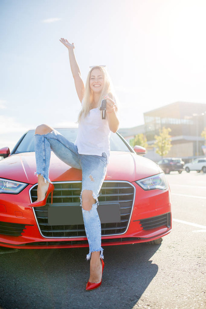 Kuva nuori nainen avaimet seisoo lähellä punainen auto
 - Valokuva, kuva