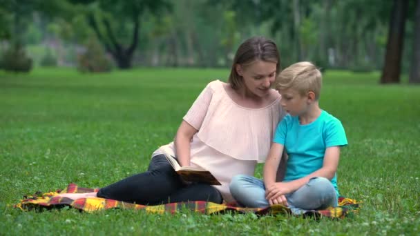Mother and son doing homework together in park, child education, parenthood - Footage, Video
