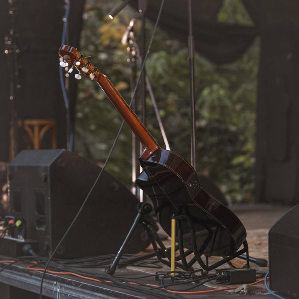 Guitare sur un stand sur une scène éclairée et équipée lors de la performance de musiciens
 - Photo, image