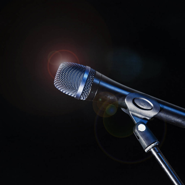 Мікрофон на тринозі стоїть на сцені, освітлені прожекторами в блакитному світлі
 - Фото, зображення