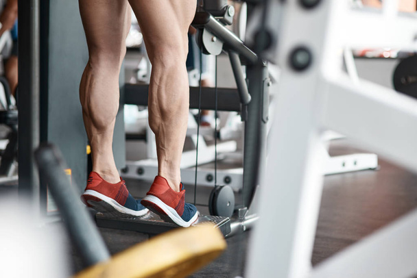 Регулярна фізична підготовка. Низький кут тренованого сильного чоловіка, який тонізує м'язи на тренажерному залі під час регулярних тренувань
 - Фото, зображення