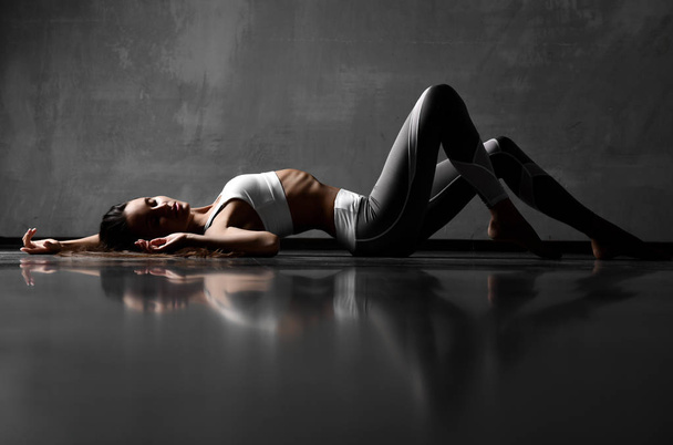 Sport woman posing lying on floor in elastic sport cloth with closed eyes  - Photo, Image
