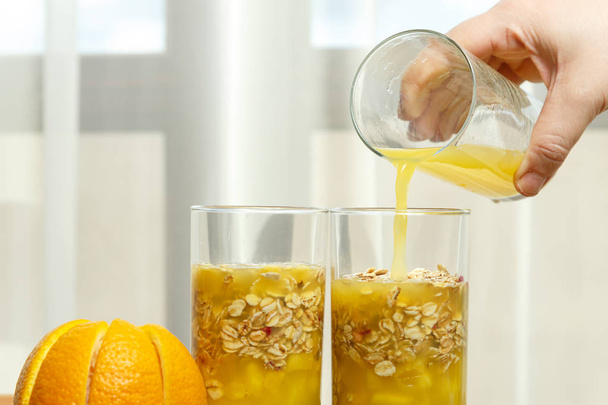 A female hand pours orange juice into glasses with pieces of fruit. horizontal photo - Fotoğraf, Görsel