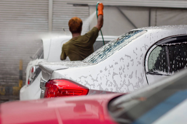 Autowäsche. männliche Arbeiter reinigen Auto mit Hochdruckwasser. Autopflegeservice. - Foto, Bild