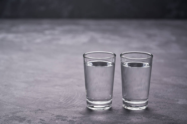 Two russian vodka shots on black table,selective focus.Vodka in shot glasses on black background - Fotó, kép