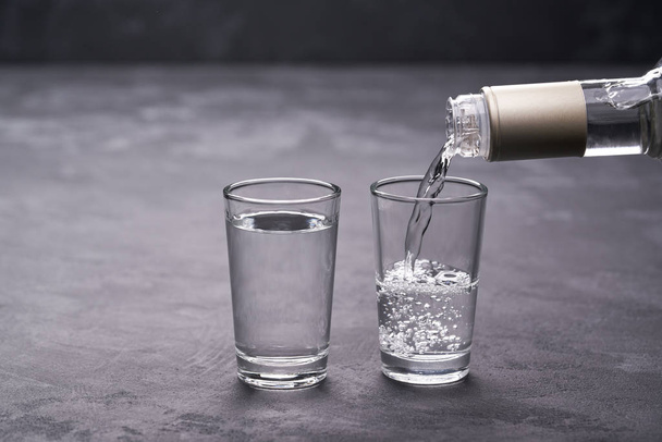 Verter vodka en el vaso sobre un fondo negro, enfoque selectivo
 - Foto, Imagen