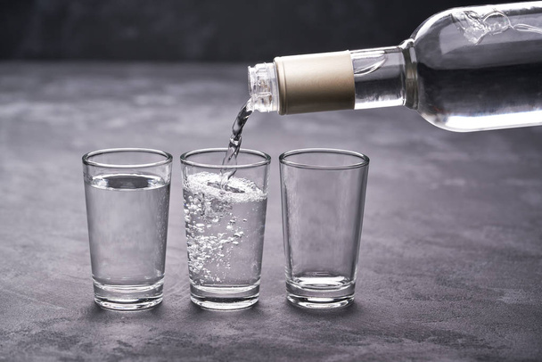 Verser de la vodka dans le verre sur un fond noir, mise au point sélective
 - Photo, image