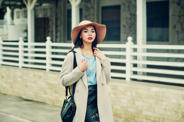Портрет молодої жінки на вулицях осіннього міста. Дівчина в широко розплавленому фетровому капелюсі і світлому пальто
 - Фото, зображення