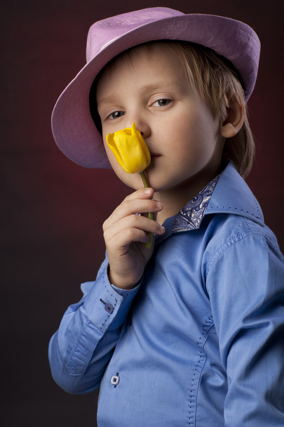 jongen in roze hoed met gele tulpen - Foto, afbeelding