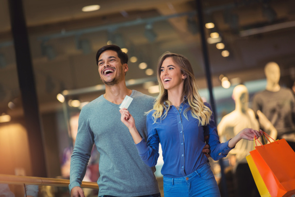 Retrato de una feliz pareja mostrando su nueva tarjeta de crédito en el centro comercial
 - Foto, imagen