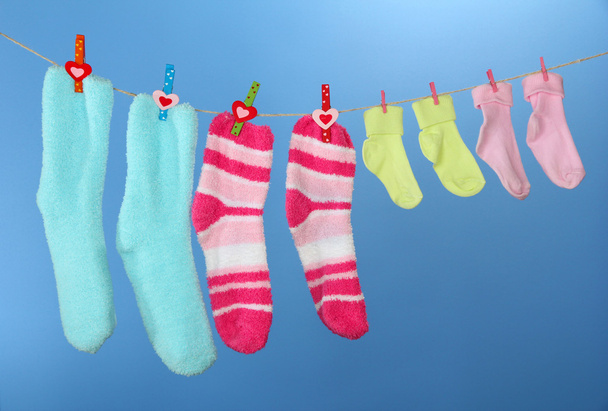 Colorful socks hanging on clothesline, on color background - Foto, afbeelding