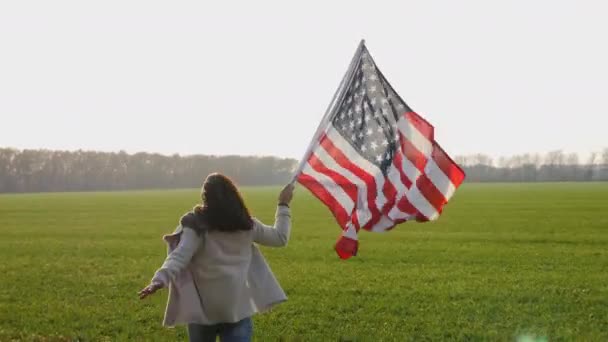 Μια γυναίκα τρέχει γρήγορα σε όλο το πεδίο με μια μεγάλη σημαία - Πλάνα, βίντεο